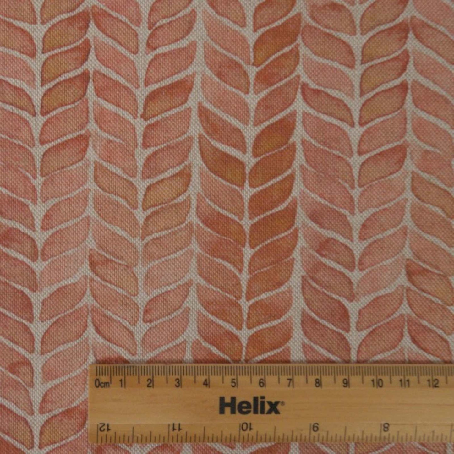 Deep pink coral fabric with rule showing the size of the leaf print stripes