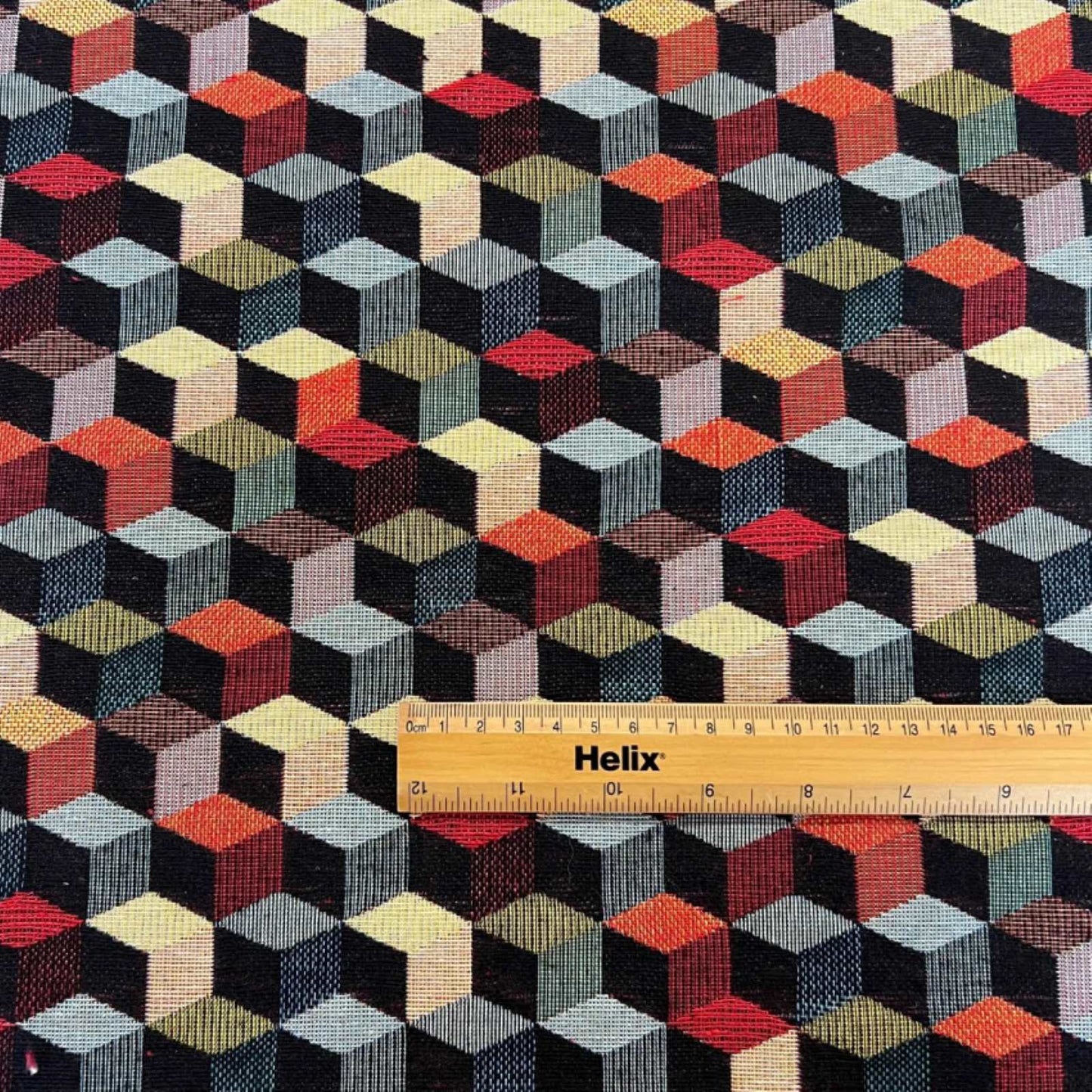 Tapestry fabric with a rule showing scale of black and multicolour tumbling blocks design