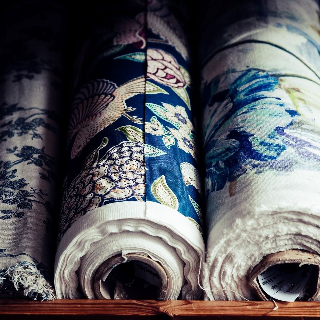 Rolls of patterned curtain fabric on a shelf