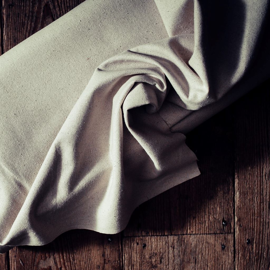 Natural coloured osnaburg fabric, swirled on a background of floorboards