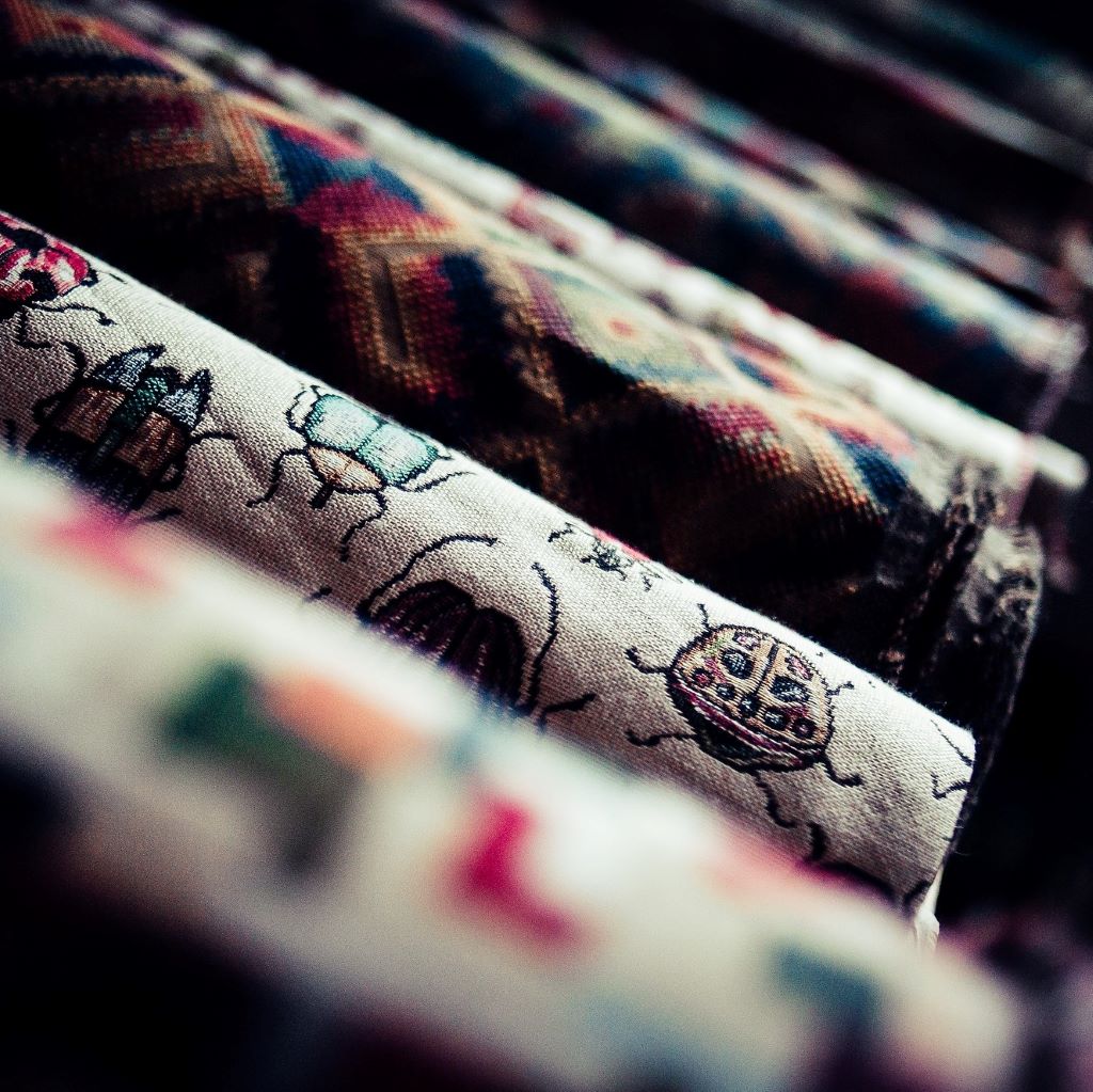 Rolls of patterned tapestry upholstery fabrics on a shelf