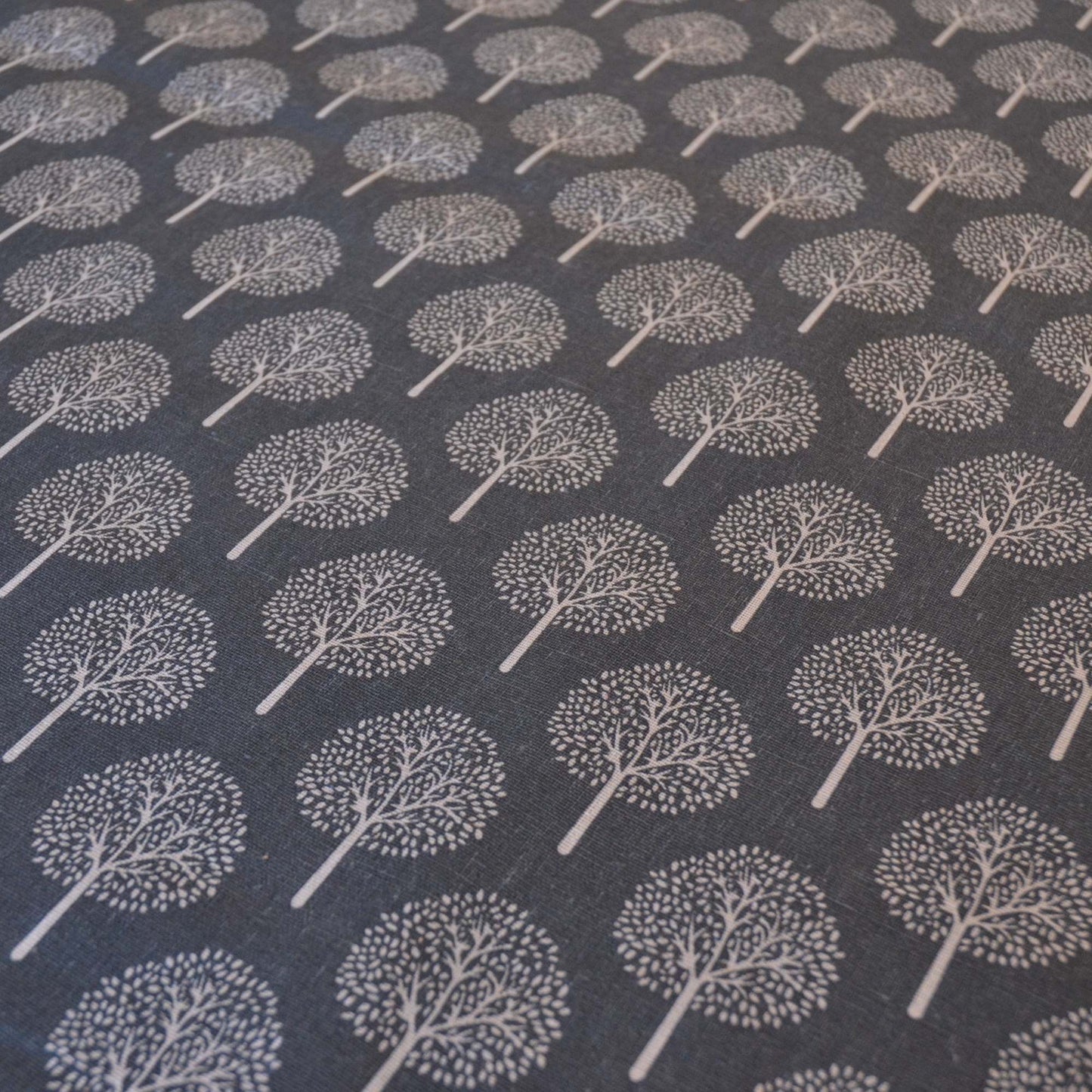 Dark Grey curtain or upholstery fabric with lighter trees, fabric shown at an angle