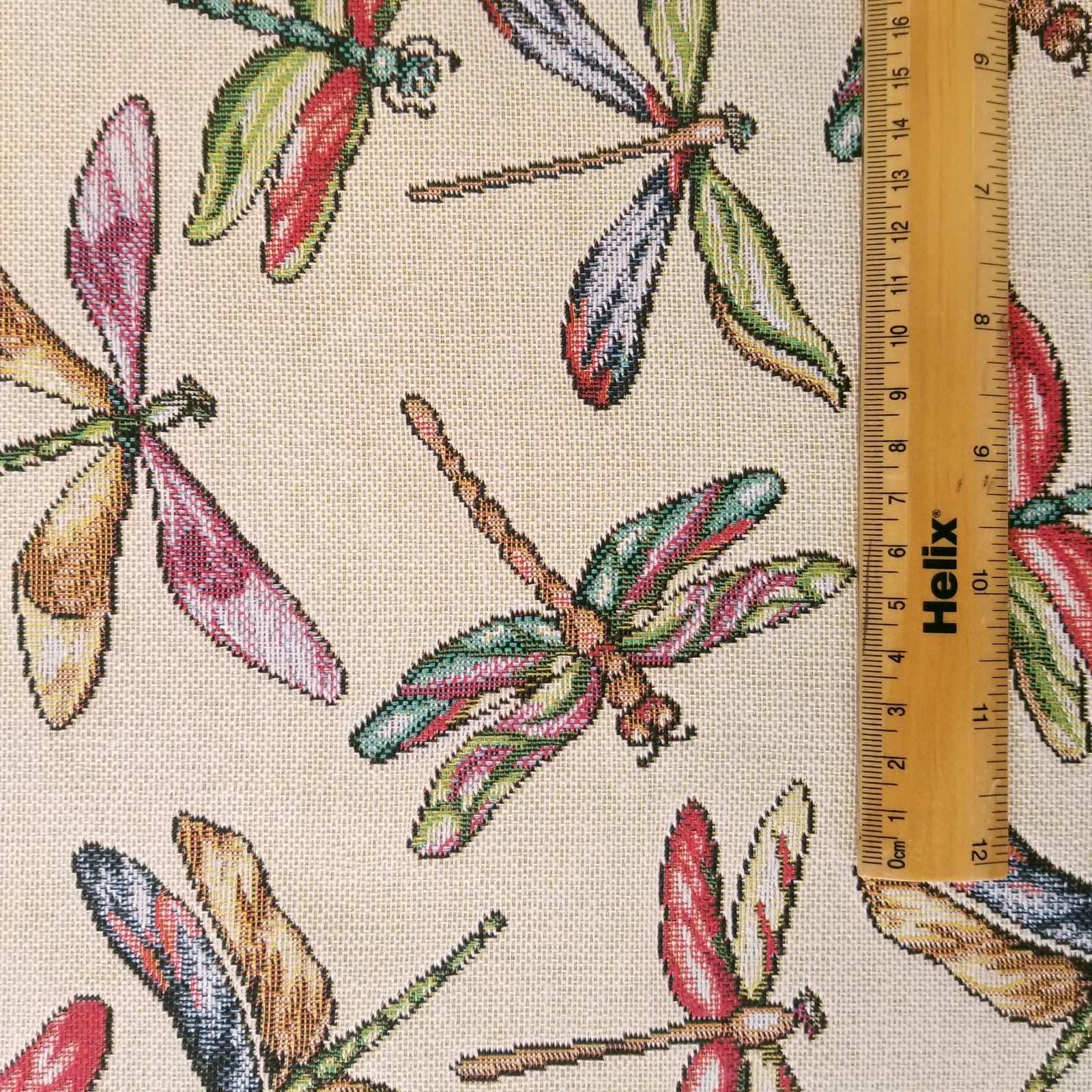 Cream tapestry fabric with a rule showing scale of colourful dragonfly design
