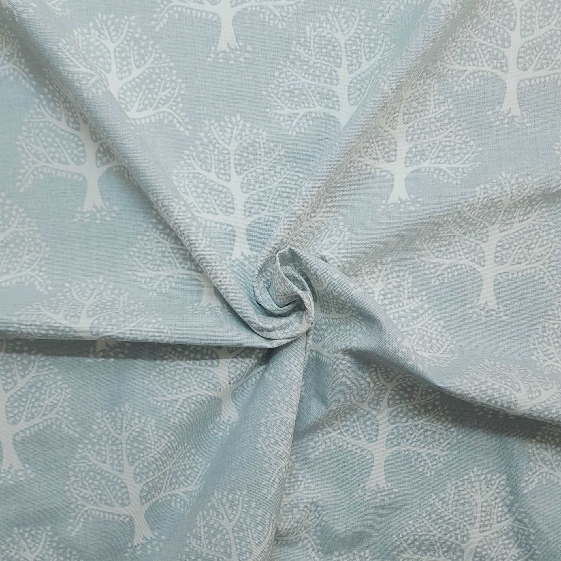Sustainable Cotton Fabric with a print of trees on a light blue background