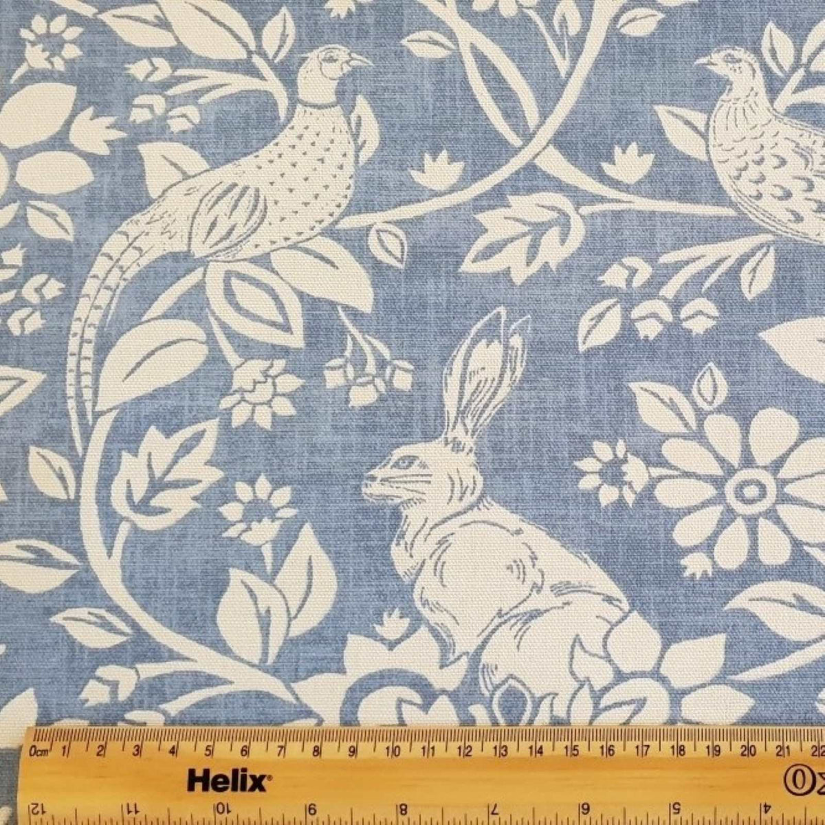 Indigo blue curtain fabric with a rule showing size of hares and pheasants design
