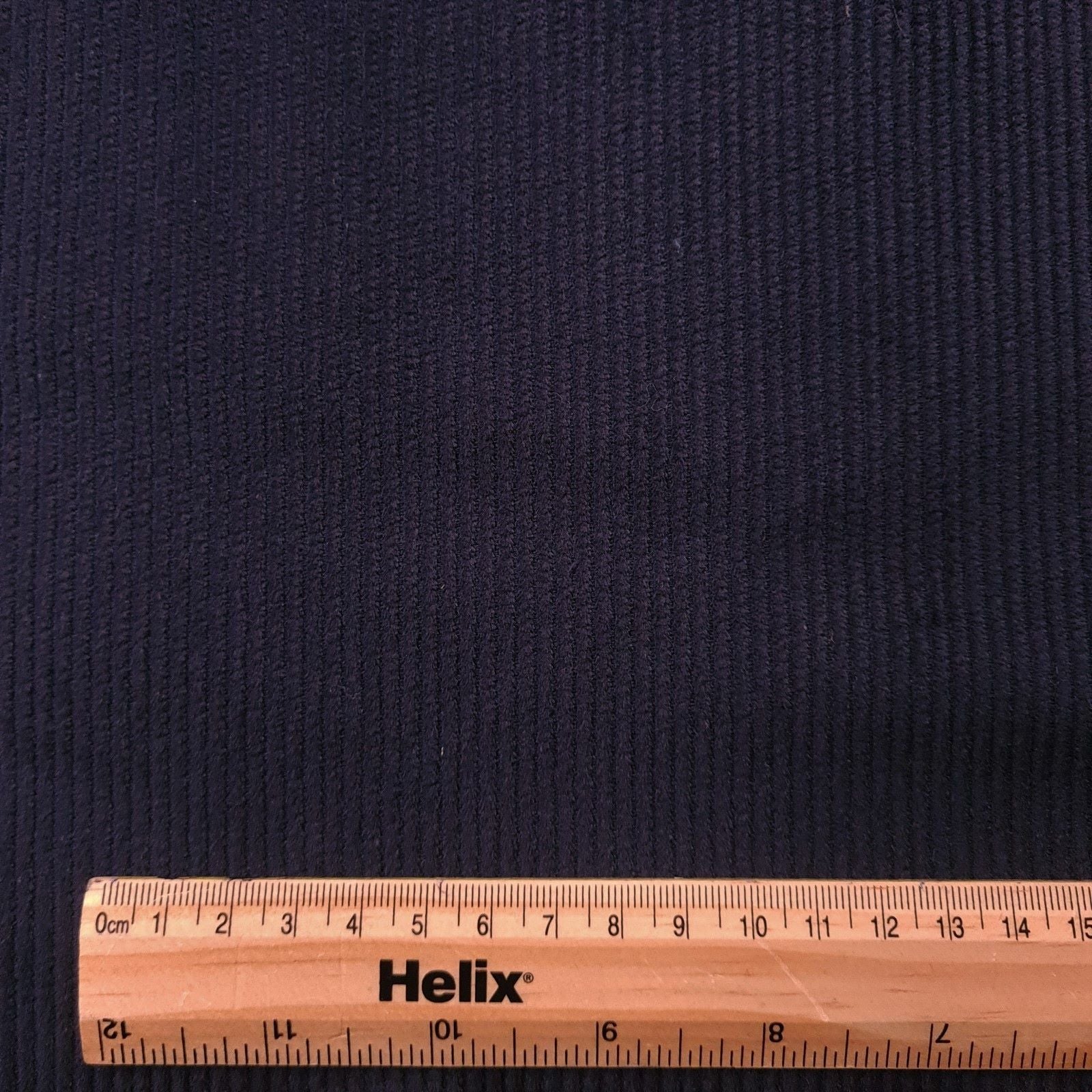Navy corduroy fabric with a ruler showing the size of the ridges in the fabric