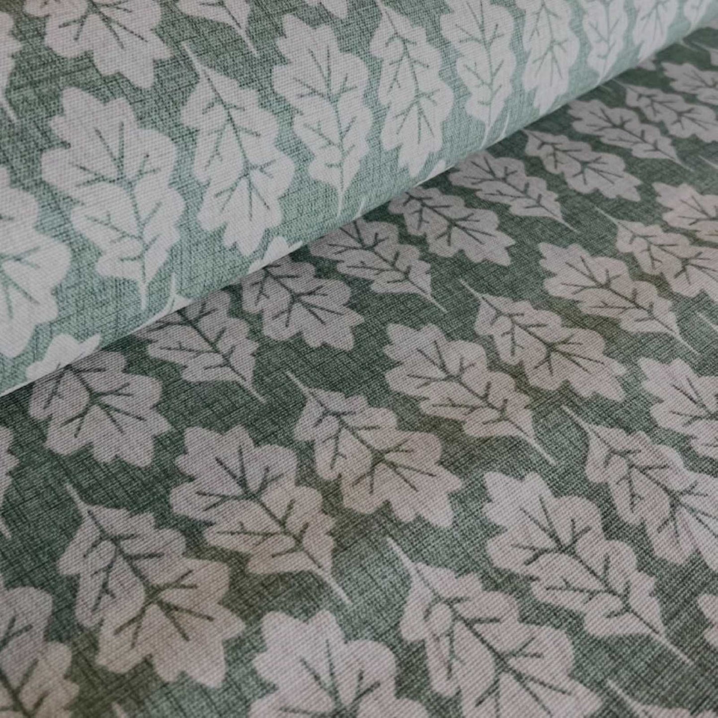 A roll of cotton curtain fabric with oak leaf print in green