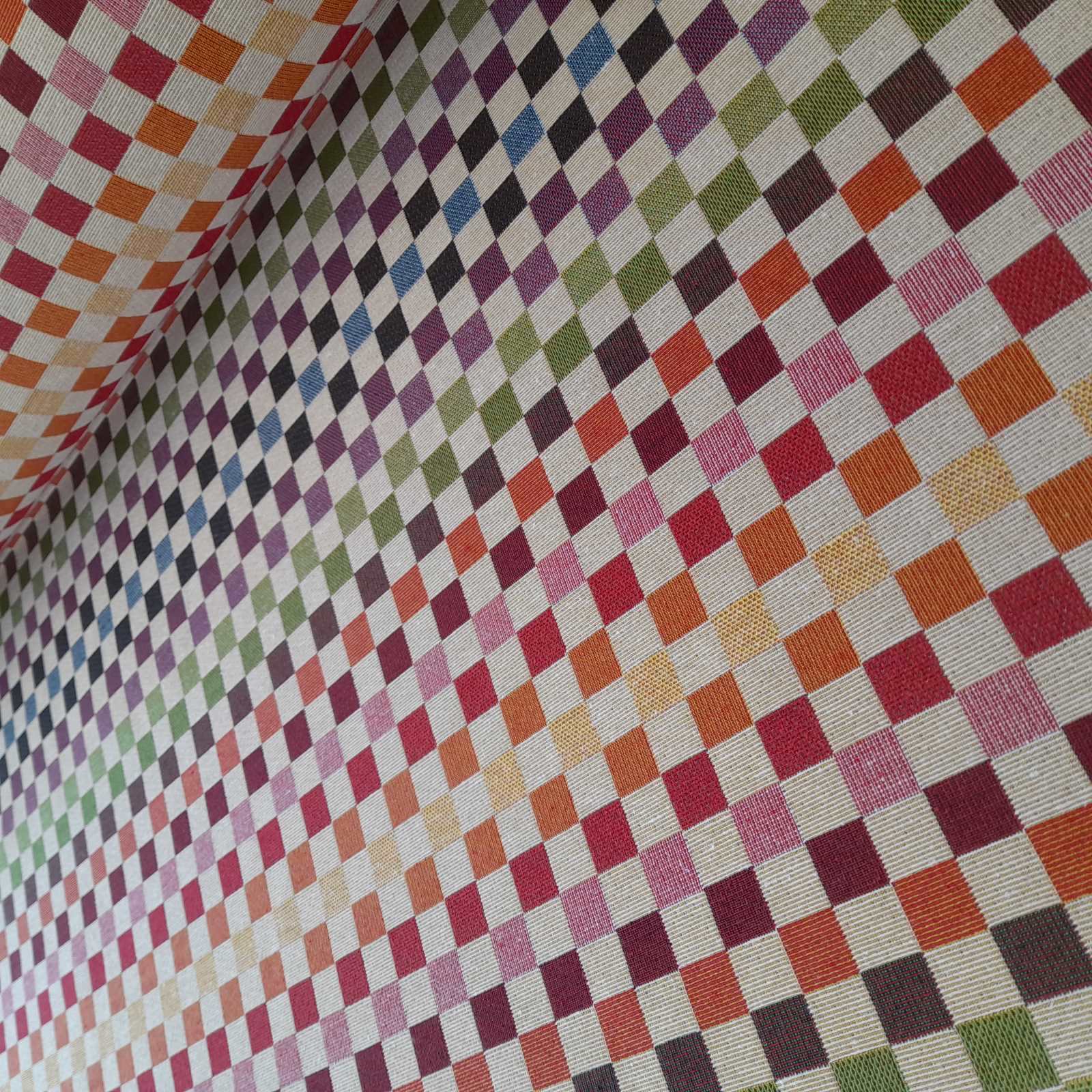A roll of tapestry fabric with small squares in rainbow colours