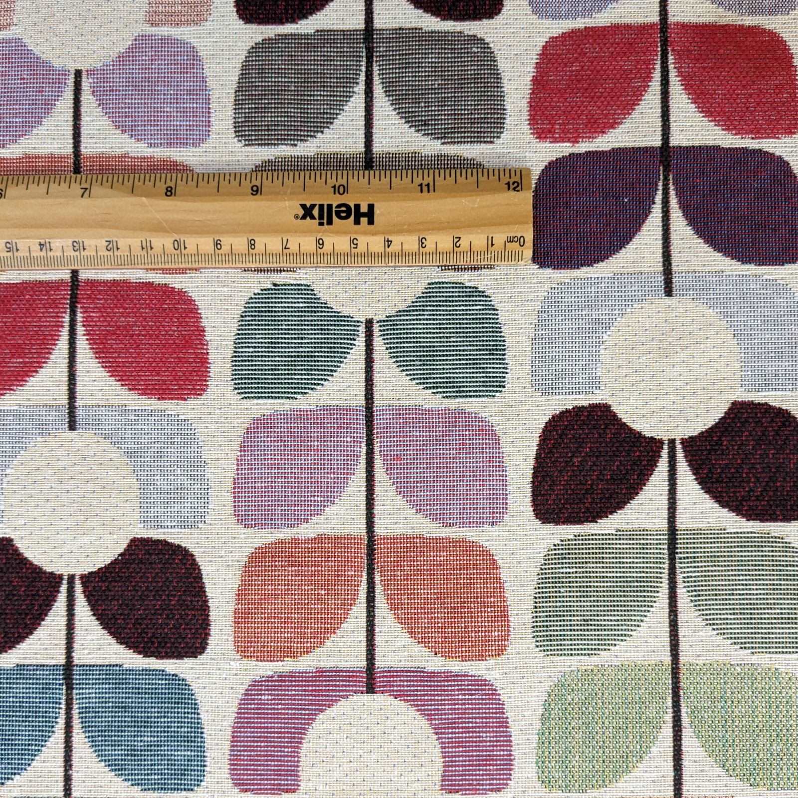 Tapestry fabric with a rule showing scale of colourful leaf sprig design