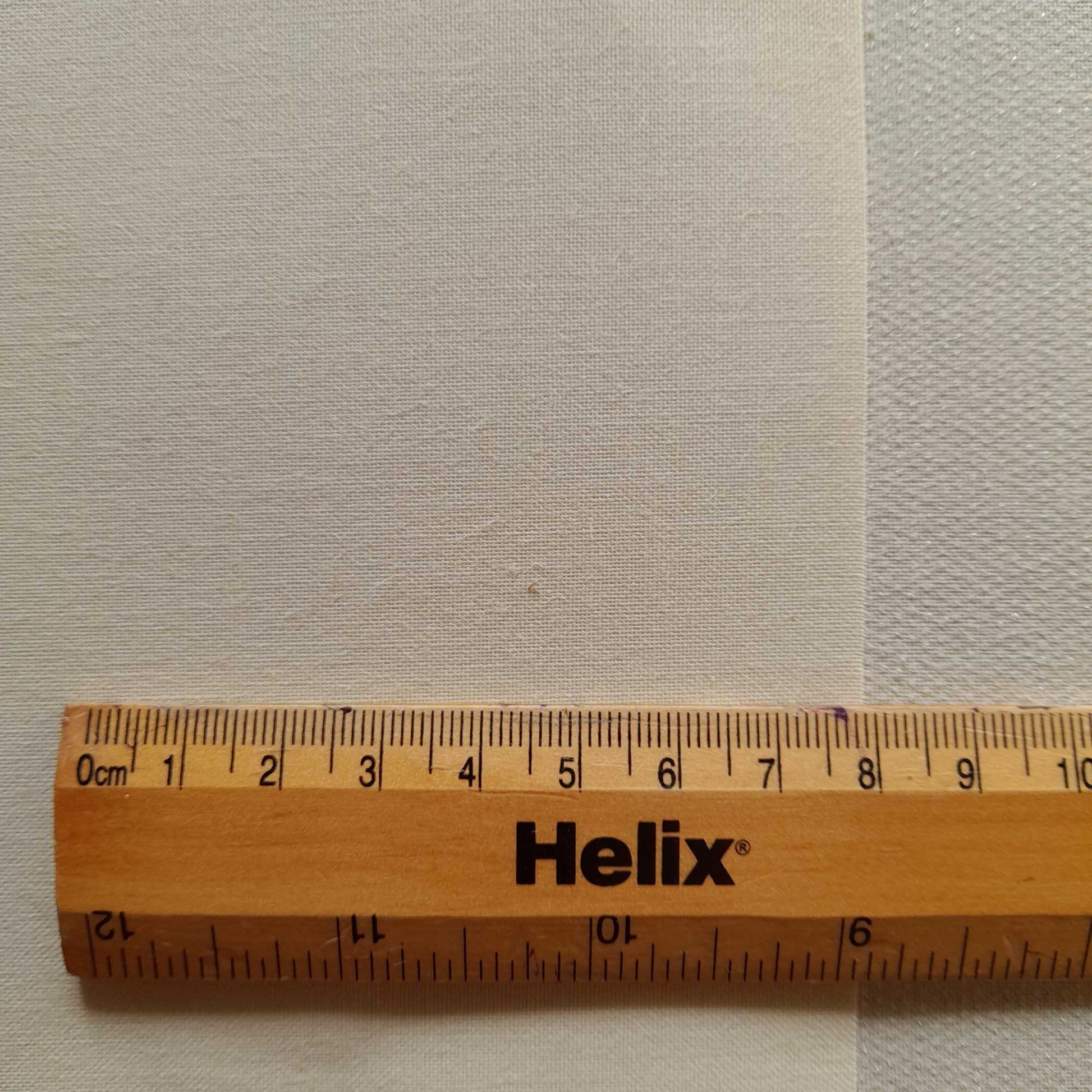 Close view of roller blind backing fabric with rule for scale