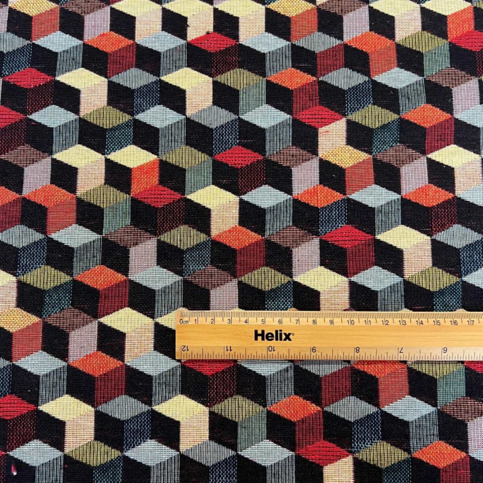 Tapestry fabric with a rule showing scale of black and multicolour tumbling blocks design