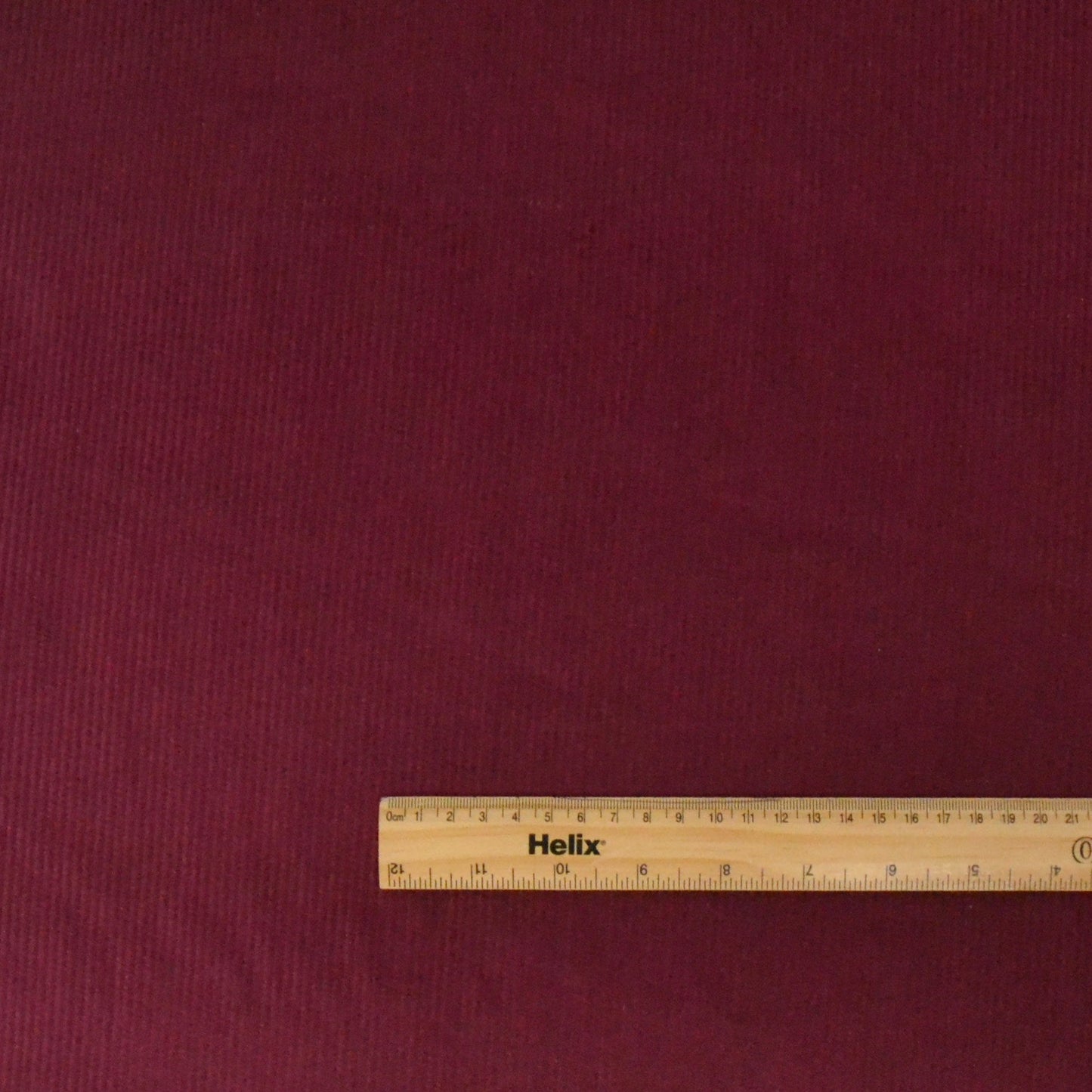 Dark Red Cotton corduroy with a ruler showing size of the ribs on the fabric